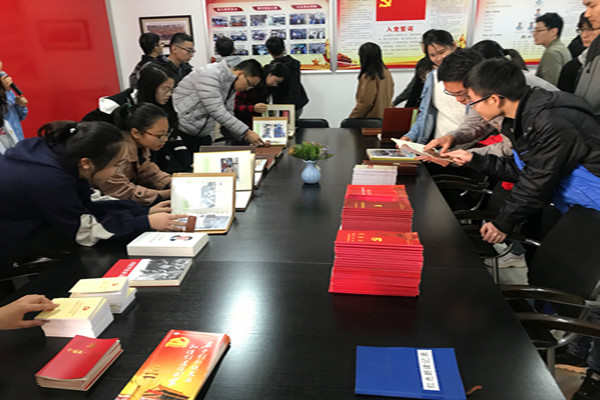 学生党员仔细阅读党员学习资料和企业珍贵文献